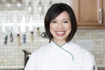 Christine Ha stands in a kitchen wearing a white chef jacket